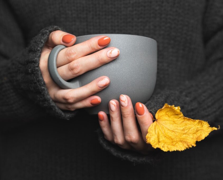 Woman holds a cup of hot tea. Grey knitted sweater